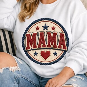 Può includere: Felpa bianca con un design circolare. Il design presenta la parola "MAMA" in rosso, circondata da un bordo a corda blu navy, stelle rosse, un cuore rosso e stelle blu navy.