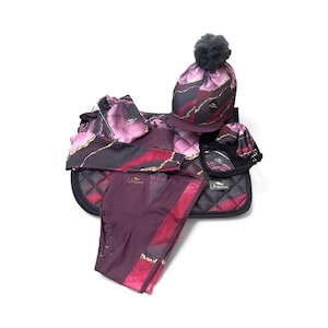 May include: A collection of equestrian gear in shades of burgundy, black, and gold. The set includes a saddle pad, riding pants, a beanie with a gray pom-pom, a riding helmet cover, and a small bag. The items feature a marbled design.