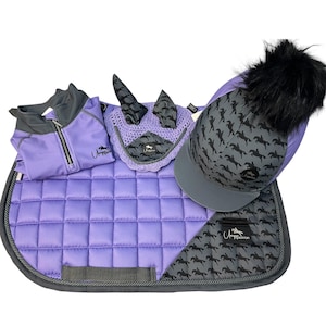 May include: An equestrian set in purple and grey, featuring a saddle pad, a fly bonnet, a show jacket, and a riding hat with a black pom-pom. The set has a repeating horse silhouette pattern.