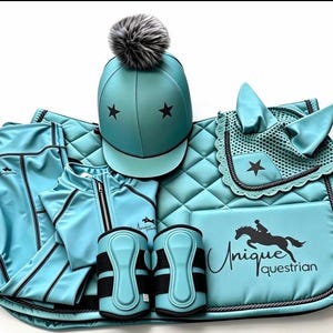May include: A turquoise equestrian set featuring a helmet with a grey pom-pom and black stars, a quilted saddle pad with the text Unique Equestrian and a horse graphic, a matching ear bonnet, a zip-up jacket, and two protective leg boots.