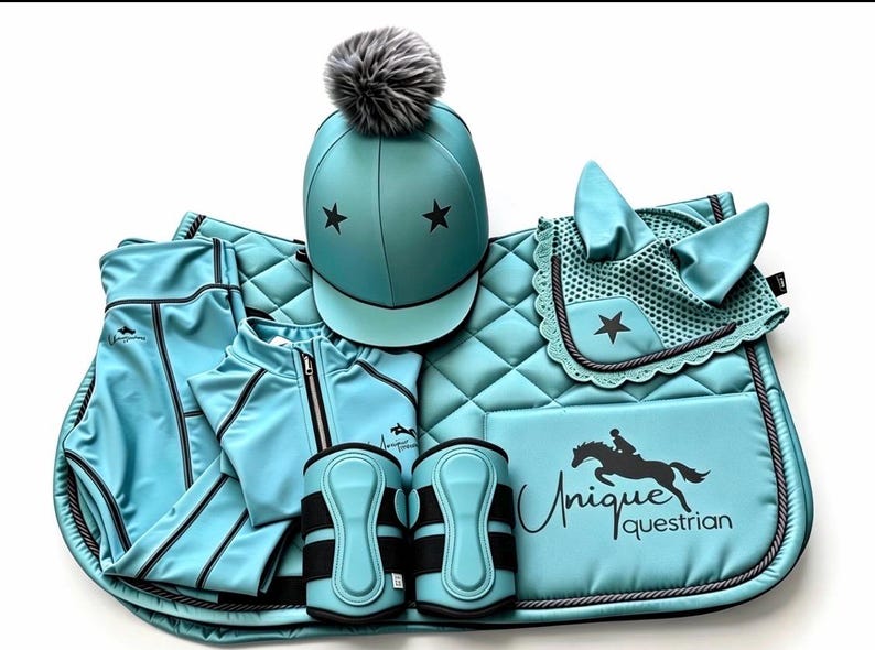 May include: A turquoise equestrian set featuring a helmet with a grey pom-pom and black stars, a quilted saddle pad with the text Unique Equestrian and a horse graphic, a matching ear bonnet, a zip-up jacket, and two protective leg boots.