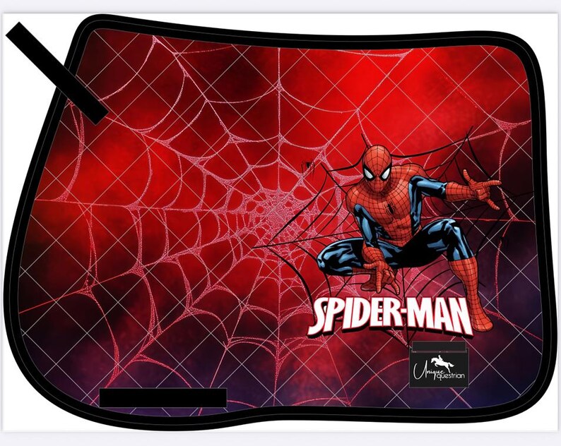 May include: A black-edged saddle pad featuring a red background with a white spiderweb design. The image includes a crouching Spider-Man graphic and the text "SPIDER-MAN". A small logo is visible at the bottom.