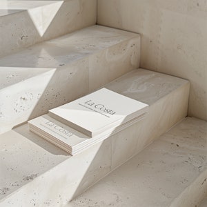 May include: A stack of white books with the title "La Costa" on the cover. The books are sitting on a set of concrete steps.