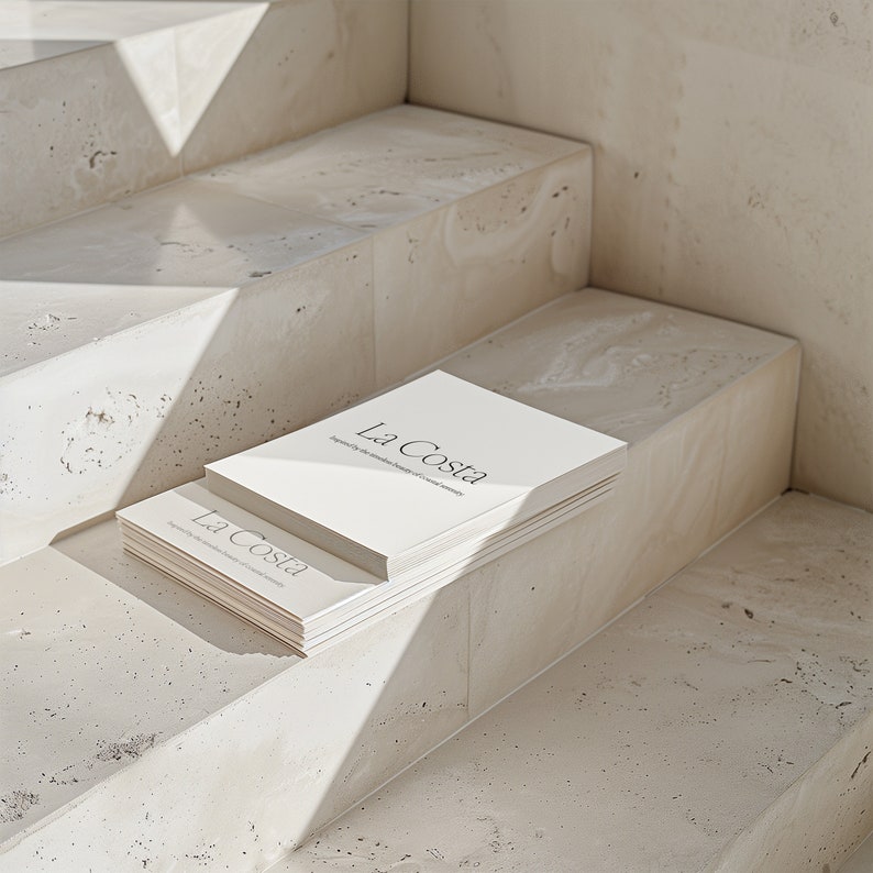 May include: A stack of white books with the title "La Costa" on the cover. The books are sitting on a set of concrete steps.