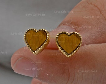 Puede incluir: Un par de pendientes de corazón de oro con incrustaciones de piedra ojo de tigre.