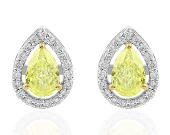 May include: A pair of stud earrings. Each earring has a pear-shaped, pale yellow gemstone encircled by a halo of smaller, clear gemstones. The setting combines gold and silver-toned metal, creating a luxurious appearance.