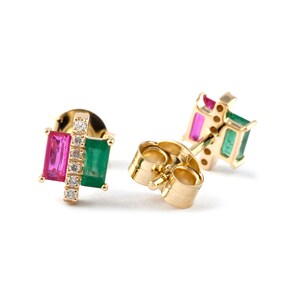 Puede incluir: Pendientes de oro con una esmeralda verde y un rubí rosa engastados en un engaste de oro. Los pendientes tienen un cierre de poste.