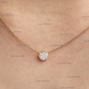 May include: A delicate gold chain necklace with a small round pendant set with sparkling white diamonds.