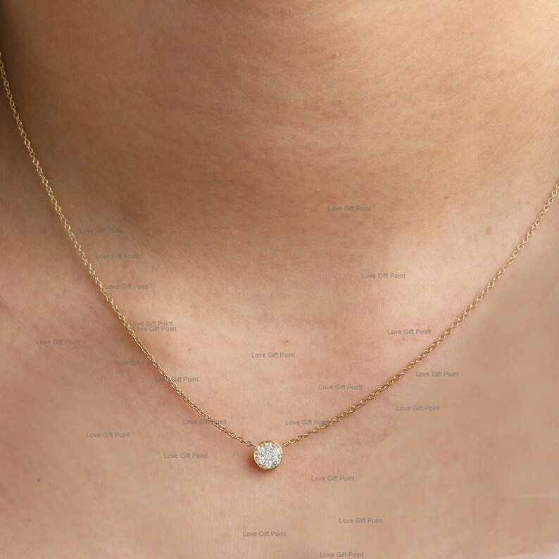 May include: A delicate gold chain necklace with a small round pendant set with sparkling white diamonds.