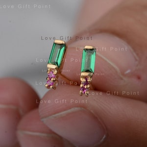 Puede incluir: Un par de pendientes de oro con piedras rectangulares de color verde esmeralda y detalles en rosa.