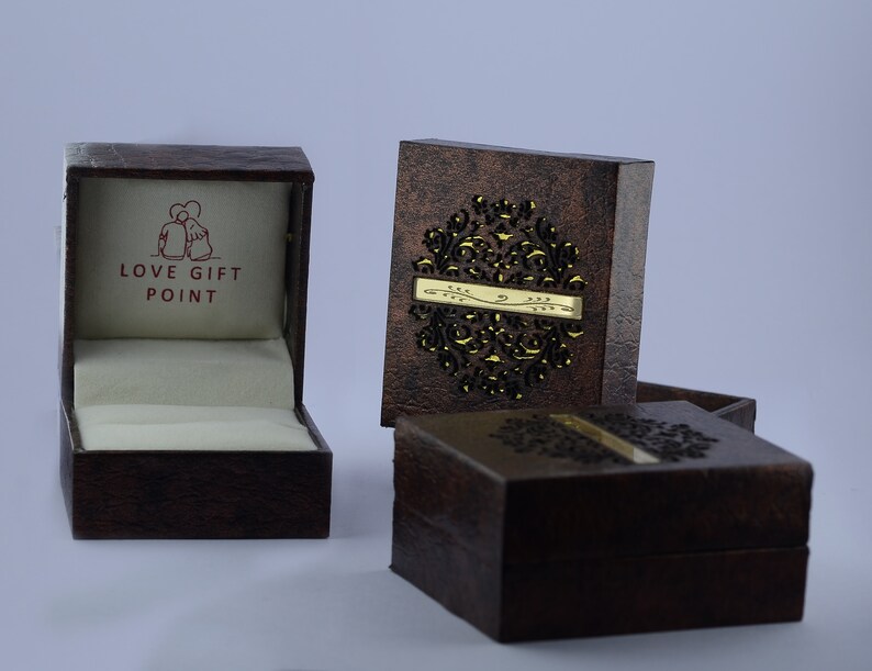 May include: Three brown boxes with intricate designs. The top box is open and has a white interior with the words "LOVE GIFT POINT" printed in red. The other two boxes are closed and have a gold design.