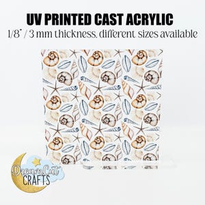 Puede incluir: Una lámina de acrílico blanco con un patrón repetitivo de conchas marinas, estrellas de mar y hojas pintadas con acuarela. El acrílico tiene un grosor de 3 mm y está disponible en diferentes tamaños. El texto "UV PRINTED CAST ACRYLIC" y "Dream Cat CRAFTS" es visible en la imagen.