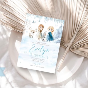 K&ouml;nnte beinhalten: Eine blaue und wei&szlig;e Einladungskarte mit einer Aquarell-Illustration von zwei M&auml;dchen und einem Rentier. Der Text auf der Karte lautet "Bitte schlie&szlig;en Sie sich uns zu einer Frozen-Feier an. Evelyn wird 5 Jahre alt. 10. Januar um 16:00 Uhr Wildflower Avenue Kalifornien 91214 RSVP Anna unter 847 484 5306".