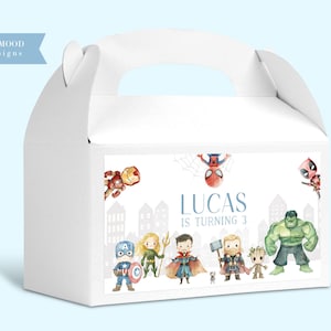 Puede incluir: Caja blanca para regalos de fiesta con asa, con ilustraciones de superhéroes y el texto "LUCAS IS TURNING 3." La caja incluye imágenes de Iron Man, Spider-Man, Deadpool, Capitán América y Hulk.