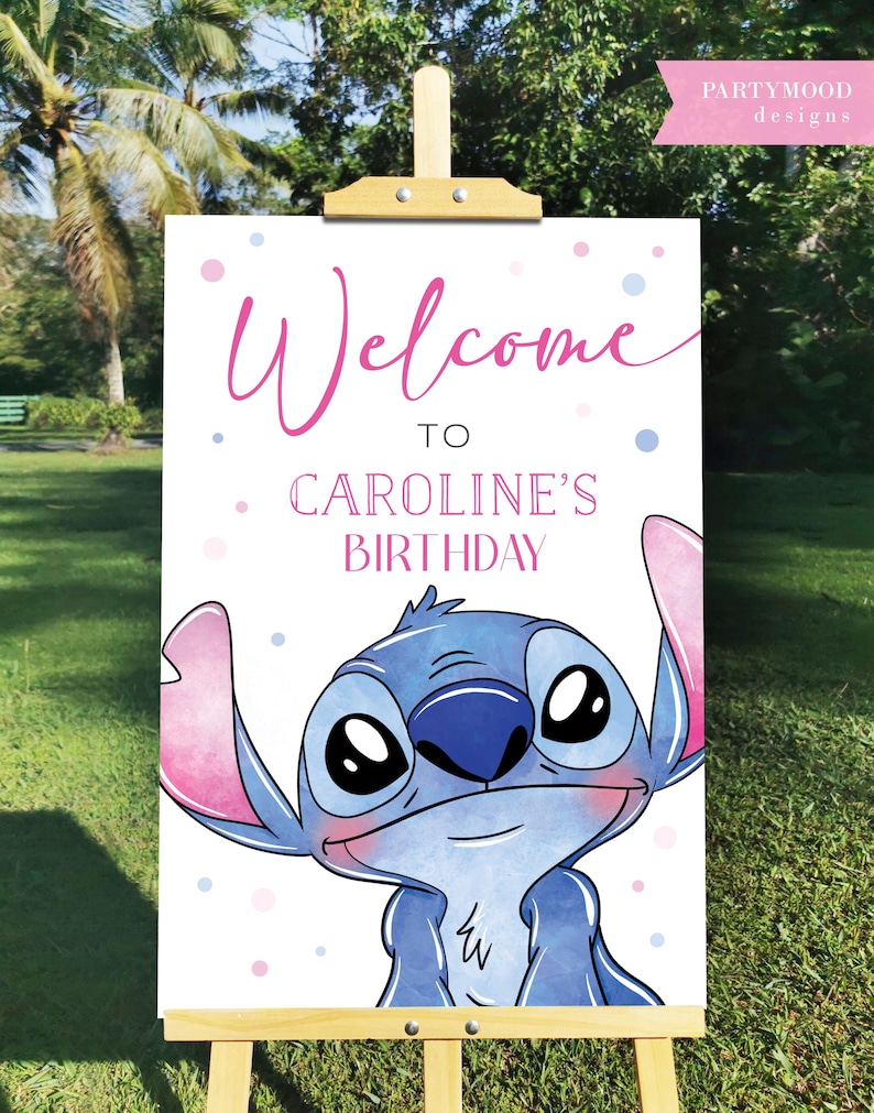 May include: A wooden easel displays a white sign with the words "Welcome to Caroline's Birthday" in pink script. A cartoon character with blue fur and large eyes is featured at the bottom. Pink and blue polka dots are scattered around the text.