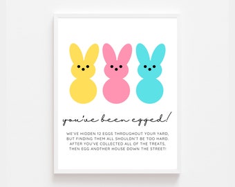 Peut inclure: Une affiche imprimable avec trois œufs de Pâques en dessin animé, un jaune, un rose et un bleu. L'affiche dit "you've been egged!" et comprend des instructions pour une chasse aux œufs de Pâques.