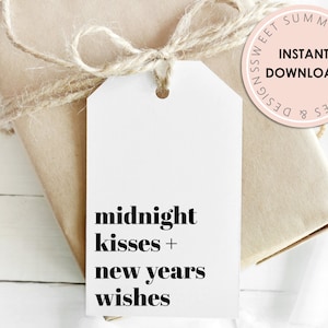 May include: A white gift tag with black text that reads "midnight kisses + new years wishes". The tag is tied with twine to a brown gift box.
