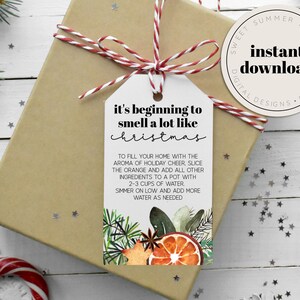 May include: A Christmas gift wrapped in brown paper, tied with red and white twine, and a tag that reads "it's beginning to smell a lot like christmas." The tag has watercolor illustrations of festive elements.