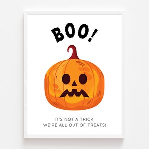 May include: A white framed print with a cartoon pumpkin with a sad face and the text "BOO! It's not a trick, we're all out of treats!"