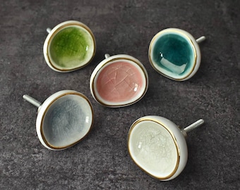 May include: Five ceramic door knobs with gold trim. The knobs are in various colors, including green, blue, pink, and gray.