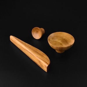 May include: Three wooden cabinet knobs in various shapes and sizes. The knobs are made of light brown wood and have a smooth, polished finish.