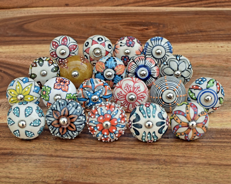 Puede incluir: Una colecci&oacute;n de 18 pomos de cer&aacute;mica con coloridos patrones florales. Los pomos son redondos y tienen una base de metal plateado.
