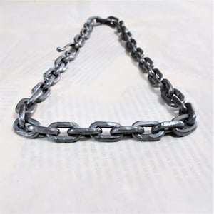 Pu&ograve; includere: Una collana a catena argentata realizzata in metallo spesso e collegato. La catena &egrave; composta da maglie ovali.