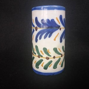 Peut inclure: Un cylindre en céramique blanche avec un motif floral bleu, vert et jaune. Le cylindre a une bordure bleue et une base bleue.