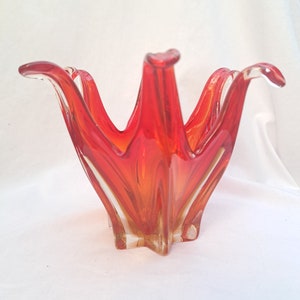 Peut inclure: Un bol en verre rouge et orange avec un motif en étoile. Le bol est en verre transparent avec un motif en spirale rouge et orange.