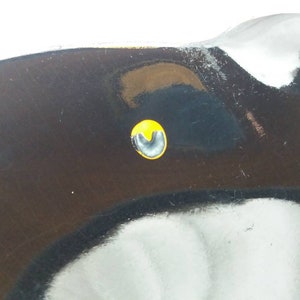 May include: Close-up of a black metal object with a yellow circle and a black U-shaped mark in the center.