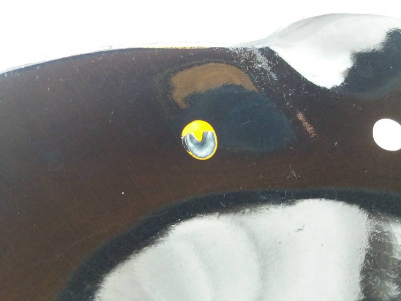 May include: Close-up of a black metal object with a yellow circle and a black U-shaped mark in the center.