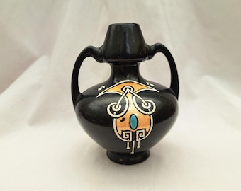 Può includere: Un piccolo vaso in ceramica nera con due manici e un design geometrico in oro e blu.