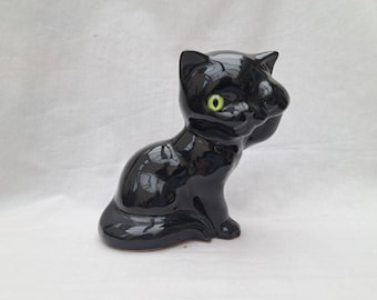 Vintage black kitten figure. Ceramic cat. Washing face. Green glass eye. Black glazed cat.