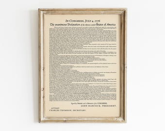 May include: A framed print of the Declaration of Independence, a historical document signed in 1776. The text is in black ink on a cream-colored background. The frame is a light wood color.