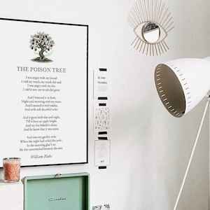 May include: A framed print of William Blake's poem "The Poison Tree" with a tree illustration. The room features a white tripod floor lamp, a decorative eye-shaped mirror, and a small green record player.