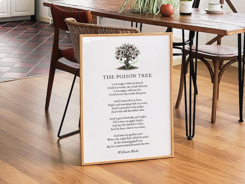 May include: A framed print of William Blake's poem "The Poison Tree" with a tree illustration and red apples. The poem is printed in black on a white background, in a light wood frame. The frame is on a wooden floor.