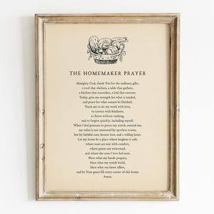 May include: Framed print featuring "The Homemaker Prayer" in black text on a cream-colored background. The print is in a distressed, light brown wooden frame. A small illustration of a basket of food is at the top.