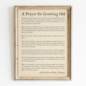 May include: A vintage-style print with a beige background and black text. The print features a prayer for growing old, written in a traditional style. The text includes phrases like "Keep me from becoming too talkative" and "Grant me the patience to listen to the complaints of others". The print is framed in a light wood frame.