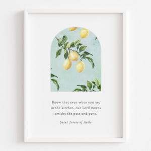May include: White framed art print featuring a watercolor illustration of lemons on a branch within an arch. The print includes a quote by Saint Teresa of Avila about faith in the kitchen.
