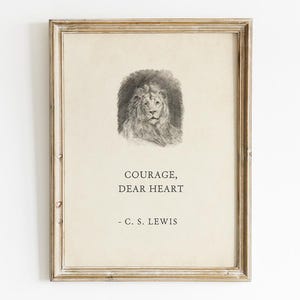 May include: Framed print featuring a detailed pencil drawing of a lion's head. The artwork is accompanied by the quote "COURAGE, DEAR HEART" by C. S. Lewis, set against a cream-colored background. The frame has a distressed, vintage look.