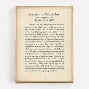 Könnte beinhalten: Gerahmter Druck mit Text aus "Briefe an einen jungen Dichter" von Rainer Maria Rilke. Der Text befindet sich auf cremefarbenem Hintergrund, goldfarben gerahmt. Der Druck zeigt den Titel, den Autor und ein Zitat.