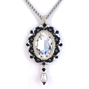 May include: A silver chain necklace with a black and silver beaded pendant featuring a large clear crystal. The pendant has a teardrop-shaped pearl hanging from the bottom.