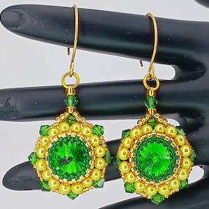 May include: A pair of gold earrings with green and yellow beads. The earrings feature a large green gemstone in the center of each earring.