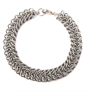 May include: A silver chain bracelet with a lobster clasp closure. The bracelet is made of interlocking metal rings.