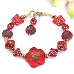 May include: Red and gold bracelet with flower and butterfly charms. The bracelet is made of glass beads and metal.
