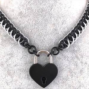 Peut inclure: Un collier de chaîne noir et argent avec un cadenas en forme de cœur noir.