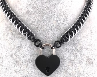 May include: A black and silver chain necklace with a black heart-shaped padlock.