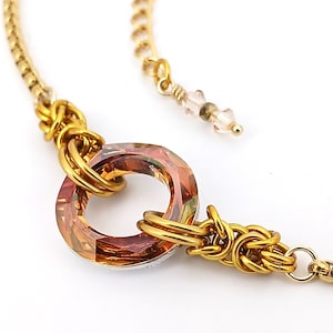 Peut inclure: Un collier en chaîne dorée avec un grand pendentif en cristal facetté de couleur ambre. Le pendentif est entouré d'un motif en fil d'or.