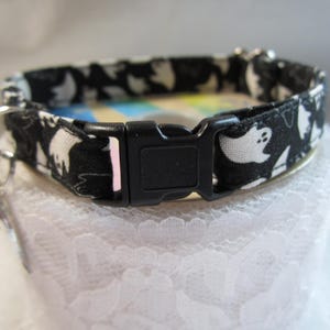 Puede incluir: Collar de gato blanco y negro con un patr&oacute;n de fantasmas. El collar tiene una hebilla de pl&aacute;stico negro.