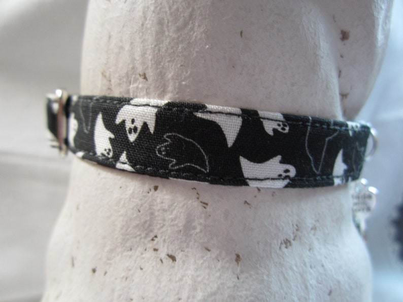 Puede incluir: Collar de perro blanco y negro con un patr&oacute;n de fantasmas.